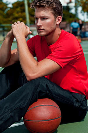 A portrait of a serene young adult white guy with short dark blond hair sitting by himself on an...
