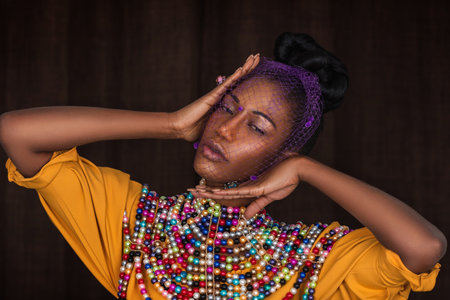 Closeup portrait of a young black woman with long hair, beautiful makeup posing by herself inside a...