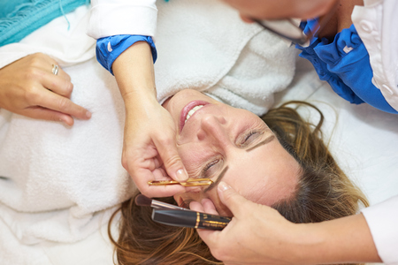 middle-aged woman getting eyebrows pluckedの写真素材