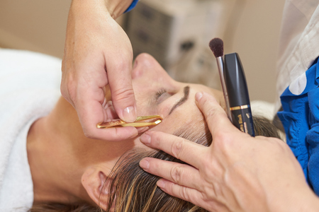 middle-aged woman getting eyebrows pluckedの写真素材