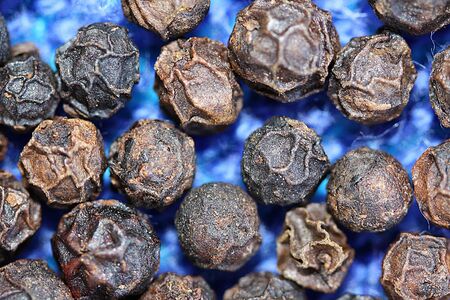 Closeup of peppercorns on a textured blue background