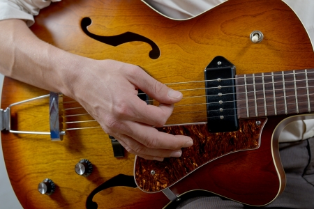 young musician playing the electric guitar, sitting on a stoolの写真素材