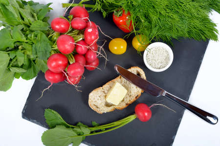 red radishes on the black plate with bread,butter and saltの写真素材