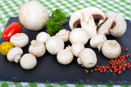 Paris mushrooms on a slate plate with tomatoesの写真素材