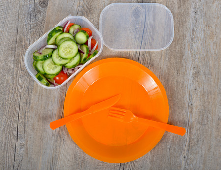 picnic consisting of an orange plate with knife and fork and a green saladの写真素材