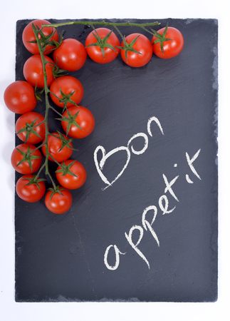 bon appetit written on a blackboard with tomatoesの写真素材