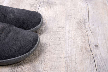 A pair of men's slippers on wooden background