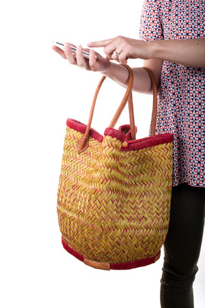 young woman holding a basket and a mobile phone on the white backgroundの写真素材