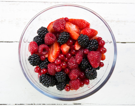 glass bowl filled with red fruits on the white table