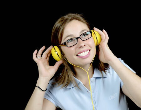 young woman listening to music with a headphone on black background