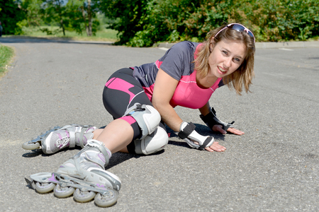 young woman dressed in pink fell on skatesの写真素材