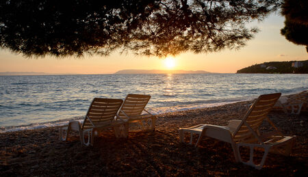 sunset at the beach with chairs の写真素材
