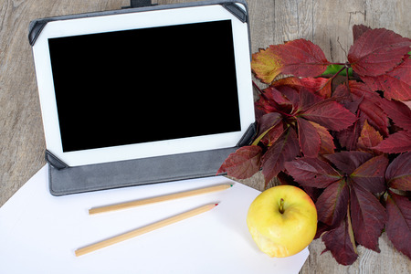Digital tablet with some pens on an old table and appleの写真素材