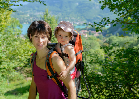 a little girl in a baby carrier walks with his momの写真素材