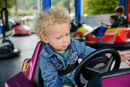 a little boy driving a bumper car at the carnival