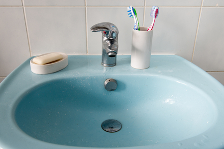 dirty bathroom sink with toothbrushesの写真素材