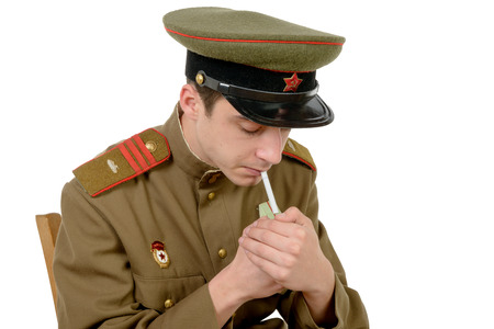a young Soviet officer sitting in a chair smoking a cigaretteの写真素材
