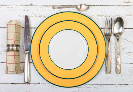 plate with silver cutlery on an old white tableの写真素材