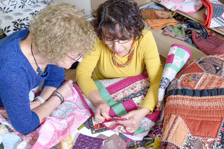 two women working on their patchwork in the workshopの写真素材