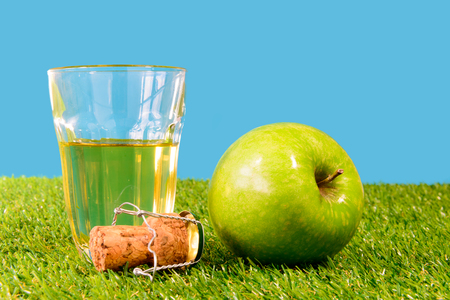 a green apple with a glass of cider on grassの写真素材