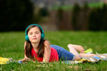 a pretty young girl listening to music in natureの写真素材