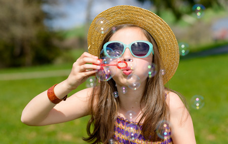 a little girl making soap bubbles in natureの写真素材
