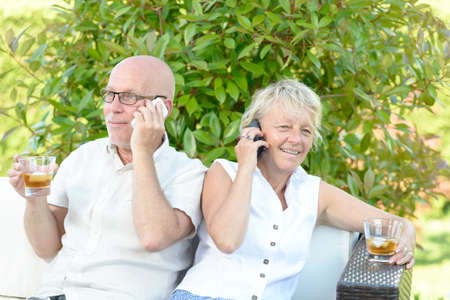 couple with their phones in their gardenの写真素材