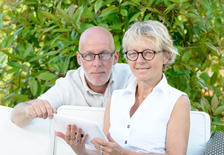 a couple of seniors looking at digital tablet outsideの写真素材
