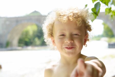 portrait of a young blonde boy playing in the riverの写真素材