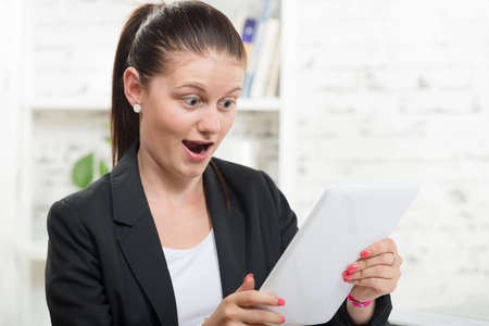 a pretty secretary looking at a digital tablet with amazementの写真素材