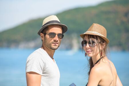 a young couple with hats near the waterの写真素材