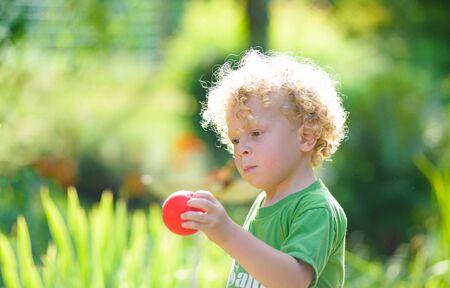 a blond child with a  small red ballの写真素材