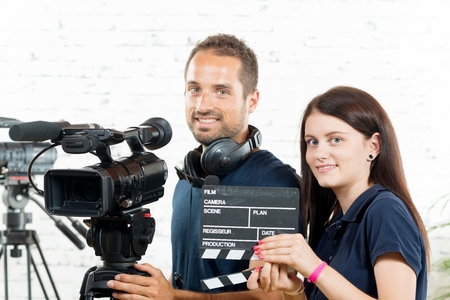 a young man and a young woman with a movie cameraの写真素材