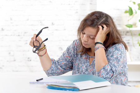 a teenage girl  with eyeglasses doing her homeworkの写真素材