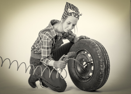 Black and white vintage and young woman inflates a car tireの写真素材