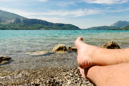 feet of man on the beach of lake of Annecyの写真素材
