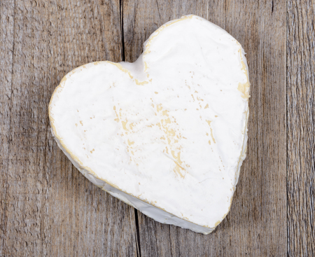 French Neufchatel cheese shaped heart on a wooden tableの写真素材