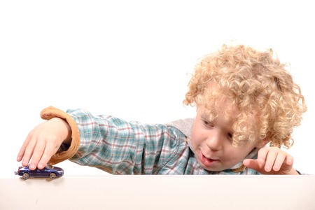 a little blond boy playing with a toy carの写真素材