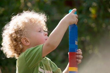 a little blonde and curly boy playing with blocks toysの写真素材