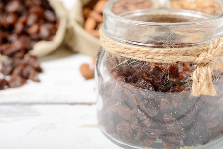 dried currants in a glass jar on wooden tableの写真素材