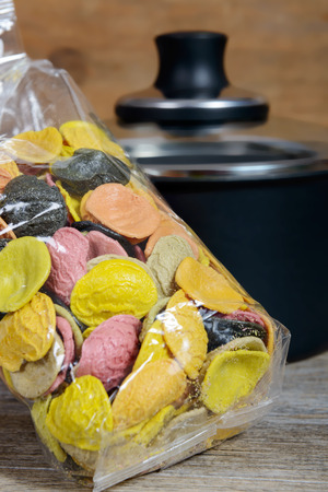 a bag of multicolored pasta, a pan in the backgroundの写真素材