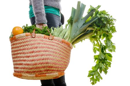 a heavy basket filled with vegetables isolated on white backgroundの写真素材