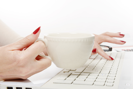 a close up of hand of woman with cup of coffee on deskの写真素材