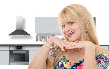 a portrait of smiling young blond housewife in modern kitchenの写真素材