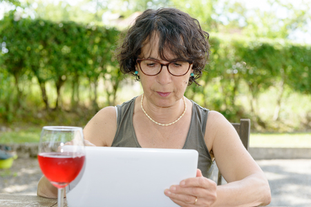 a charming  woman with a tablet in her gardenの写真素材