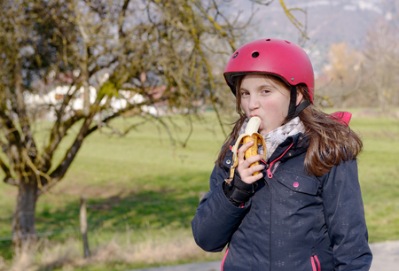 a preteen with roller skate helmet, eat bananaの写真素材