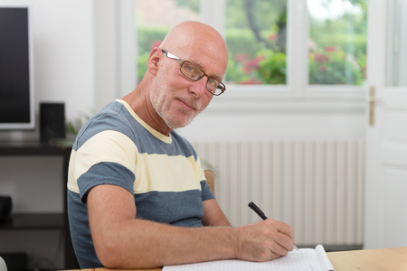 a senior man writing on a notebookの写真素材