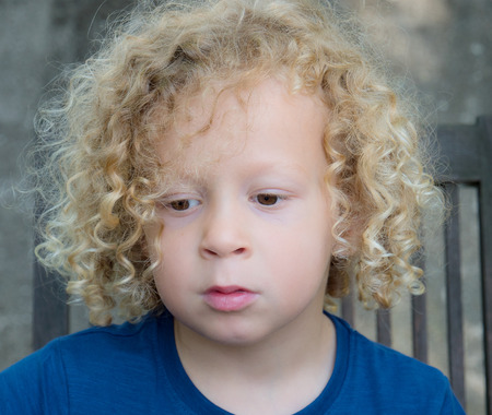 a portrait of a little boy with blond curly hairの写真素材