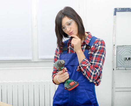 pretty young brunette woman holding cordless drillの写真素材