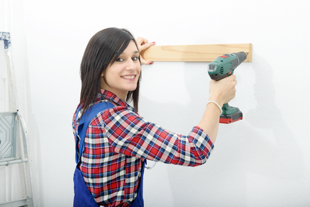 pretty young brunette woman holding cordless drillの写真素材